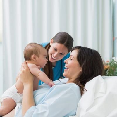 Mother holding her baby in diaper with a doctor