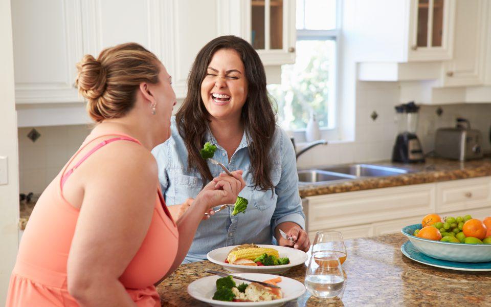 Two Women eating Healthy Meal In Kitchen